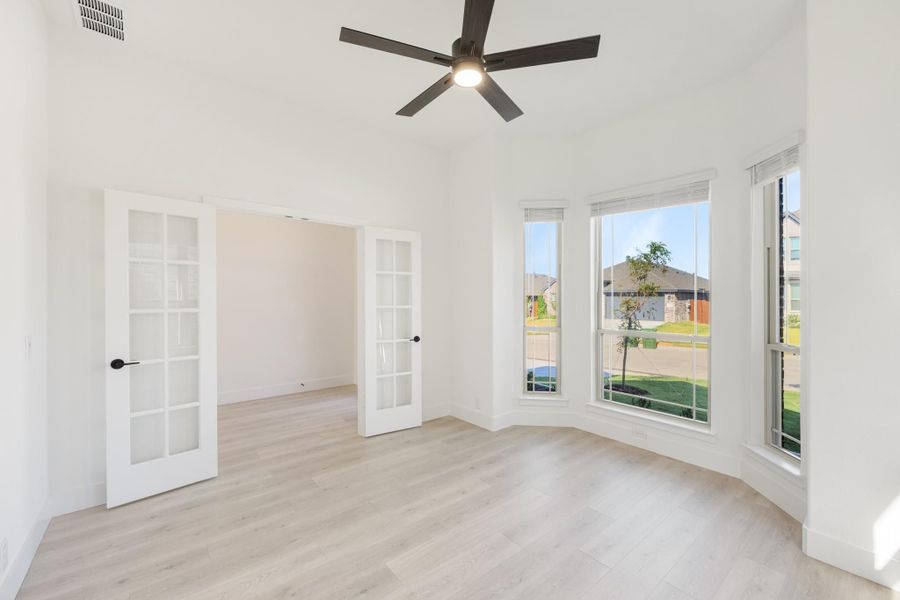 Empty room with light wood floors, French doors, bay windows, and ceiling fan Empty room with light wood floors, French doors, bay windows, and ceiling fan