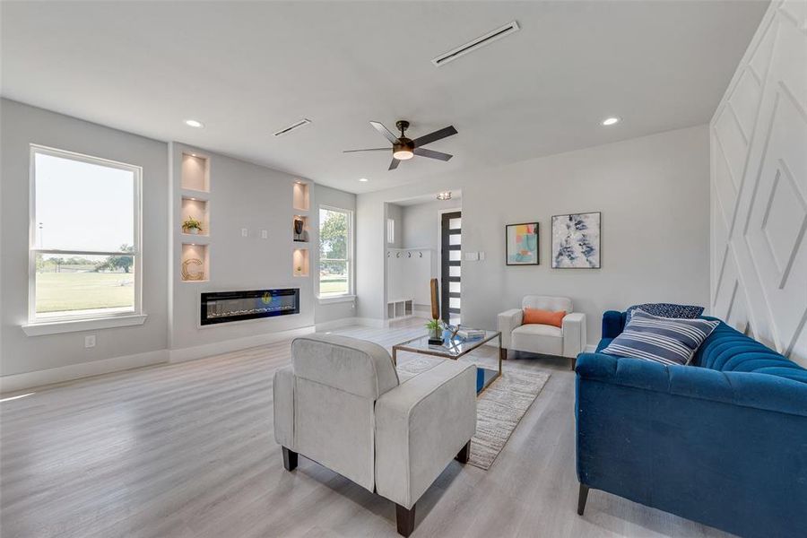 Living room with light wood-type flooring, ceiling fan, and built in features