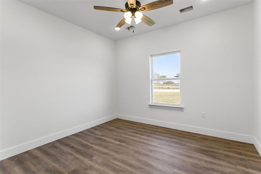 Empty room featuring ceiling fan and dark hardwood / wood-style flooring