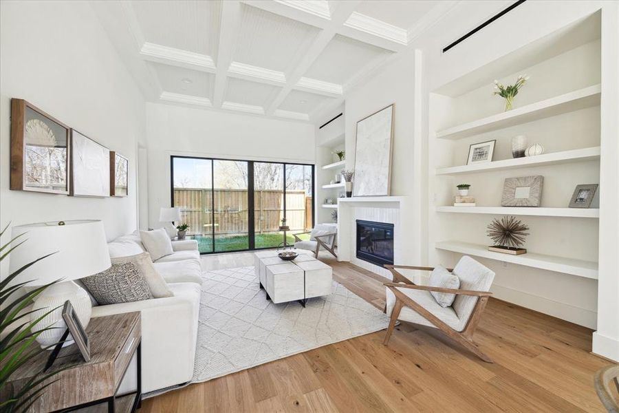 Open and Inviting - This Luxurious family room features a coffered ceiling, a brilliant fireplace flanked by shelving on both sides anchored by wide planked hardwood engineered floors. It exudes both warmth and sophistication Glass expanse doors open to the backyard seamlessly blending indoor outdoor living.