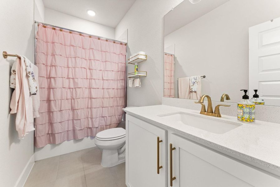 The third full bath has tile flooring and a standard-sized tub & shower with tile surround.
