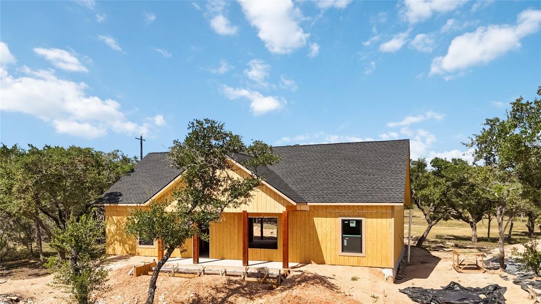 View of front facade featuring a shingled roof and a patio View of front facade featuring a shingled roof and a patio