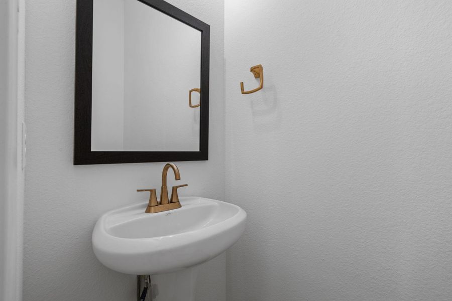 The powder room adds a thoughtful touch with soft gold finishes and understated framed mirror.