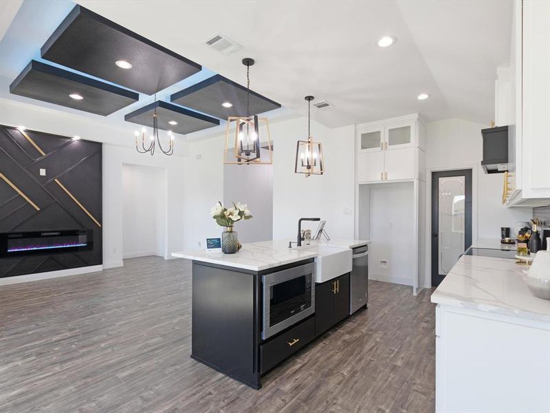 Kitchen featuring an island with sink, appliances with stainless steel finishes, dark hardwood / wood-style flooring, white cabinetry, and pendant lighting