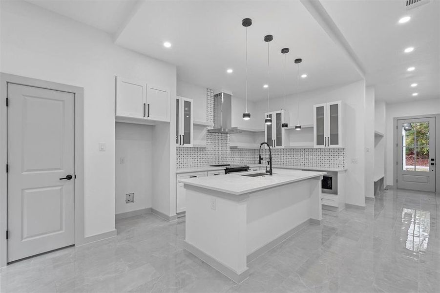 Kitchen with white cabinets, pendant lighting, sink, and a kitchen island with sink