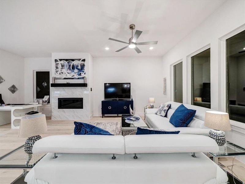 Living area featuring a premium fireplace, recessed lighting, light wood-type flooring, and ceiling fan Living area featuring a premium fireplace, recessed lighting, light wood-type flooring, and ceiling fan