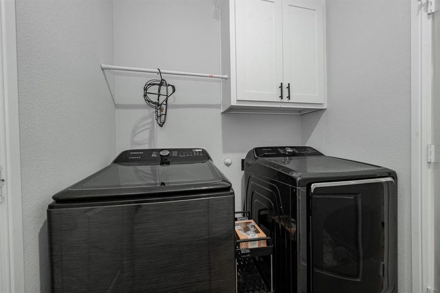 Washroom featuring cabinet space, separate washer and dryer, and a textured wall Washroom featuring cabinet space, separate washer and dryer, and a textured wall