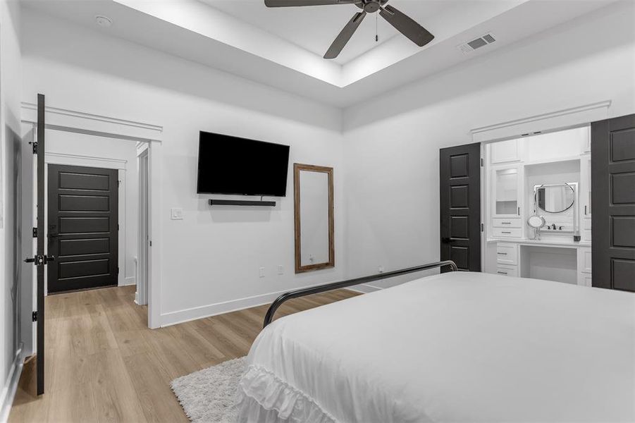 Primary Bedroom ither view featuring a raised ceiling, ensuite bathroom and light wood-style flooring. Primary Bedroom ither view featuring a raised ceiling, ensuite bathroom and light wood-style flooring.