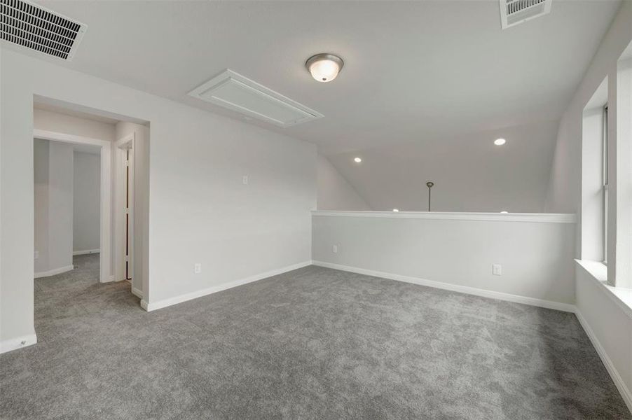 Carpeted loft space featuring light gray walls, white trim, a semi-flush mount ceiling fixture, and recessed lighting