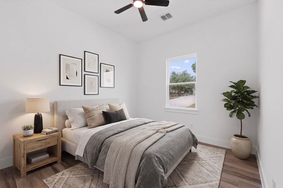 A well-lit bedroom features hardwood flooring and a functional ceiling fan for optimal comfort.