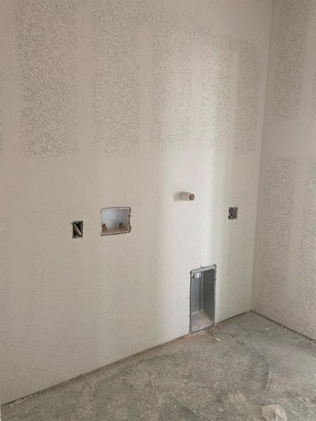 Laundry area with unfinished drywall, concrete flooring, and necessary plumbing/electrical rough-ins