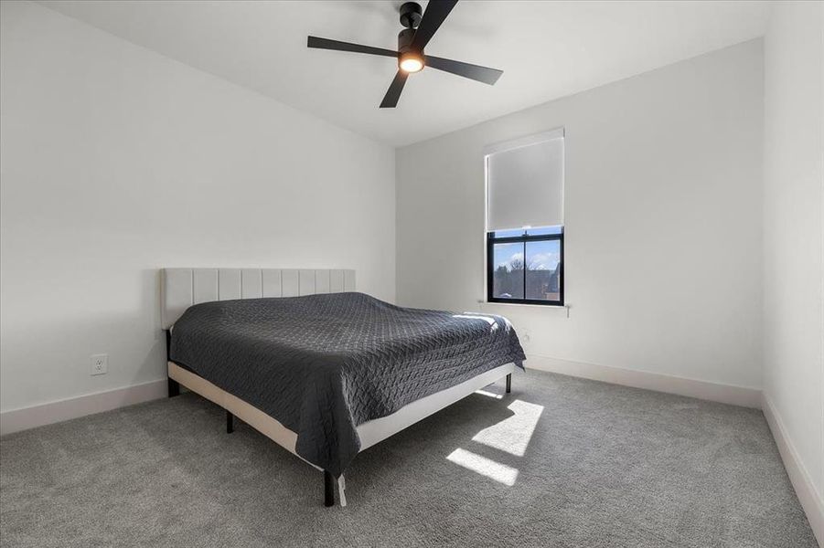 Secondary bedroom faces front of home.  Fully carpeted with ceiling fan & custom pull down blinds.