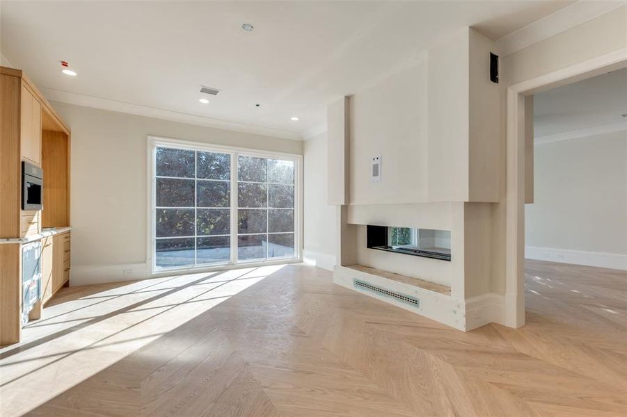 Unfurnished living room with light parquet floors and ornamental molding