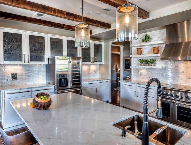 Kitchen featuring a sink, tasteful backsplash, stainless steel appliances, wall chimney exhaust hood, and light stone countertops