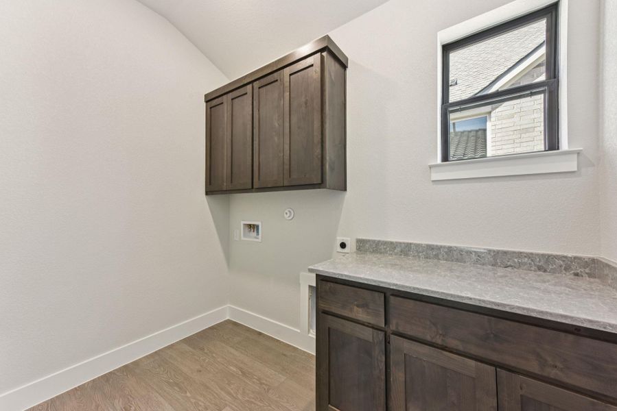Laundry room featuring light wood-type flooring, electric dryer hookup, washer hookup, cabinet space, and lofted ceiling Laundry room featuring light wood-type flooring, electric dryer hookup, washer hookup, cabinet space, and lofted ceiling