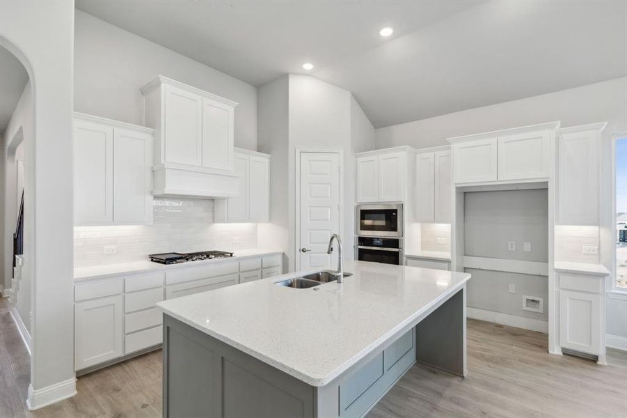 Kitchen with a center island with sink, white cabinets, stainless steel appliances, and sink