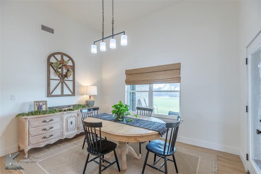 Dining space with a towering ceiling and light wood-style floors Dining space with a towering ceiling and light wood-style floors