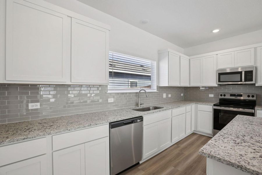 Kitchen featuring white cabinetry, stainless steel appliances, dark wood finished floors, light stone counters, and recessed lighting