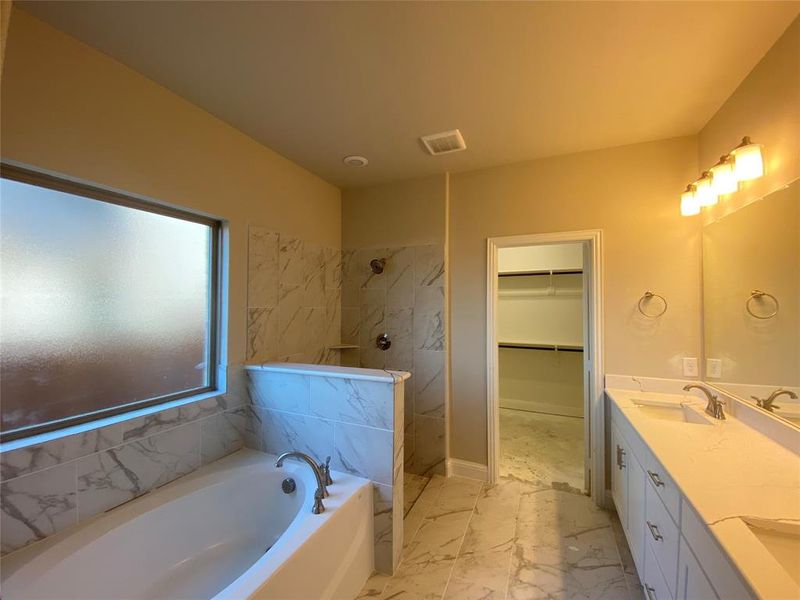 Master bath has dual sinks on Monet Quartz vanity, White Shaker cabinets, garden tub, and walk-in shower.