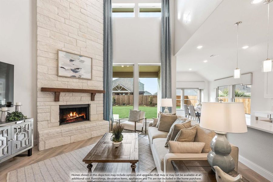 Living room with two-story stone fireplace, vaulted ceiling, and large windows overlooking backyard
