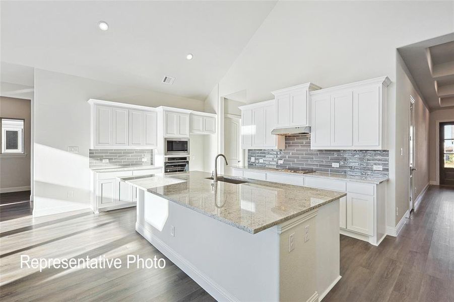 Kitchen featuring backsplash, sink, stainless steel appliances, and white cabinets