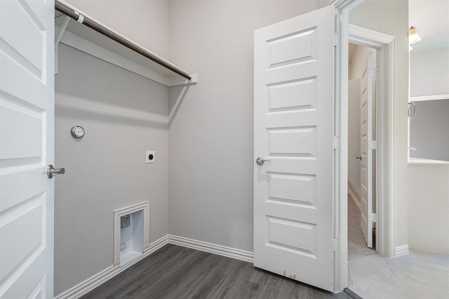 Laundry room with electric dryer hookup and dark hardwood / wood-style floors