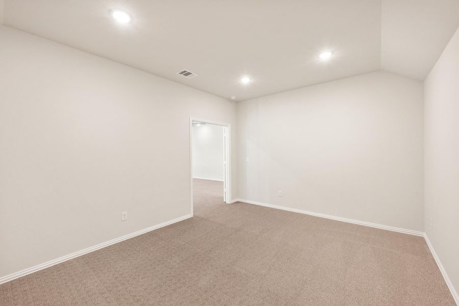Empty bedroom with beige carpet, white walls, recessed lighting, and an open doorway leading to a closet or hallway. Empty bedroom with beige carpet, white walls, recessed lighting, and an open doorway leading to a closet or hallway.