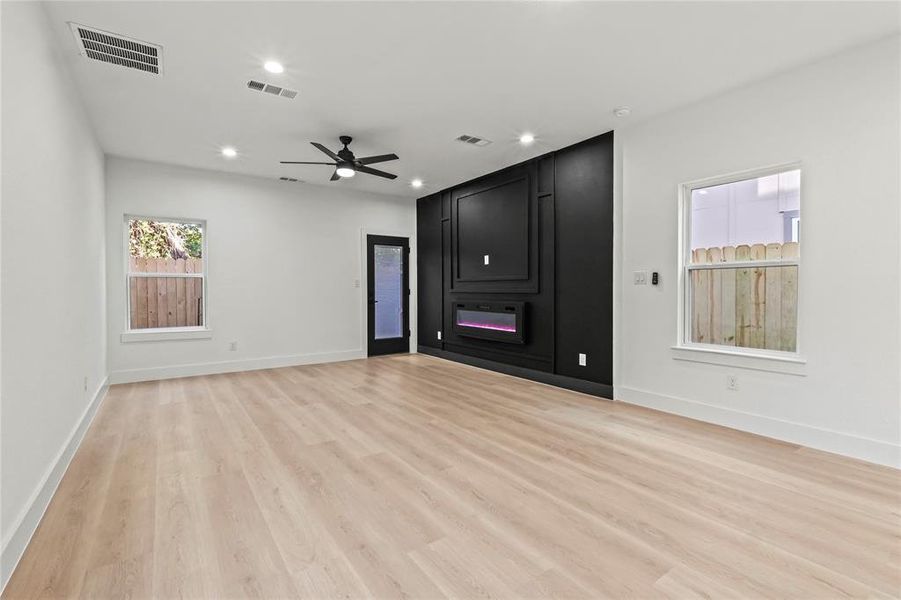 Unfurnished living room with light wood-style floors, a ceiling fan, a fireplace, and recessed lighting Unfurnished living room with light wood-style floors, a ceiling fan, a fireplace, and recessed lighting