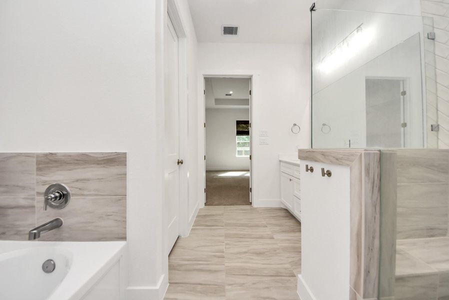 Another view of primary bathroom showcasing tub, shower and counters.