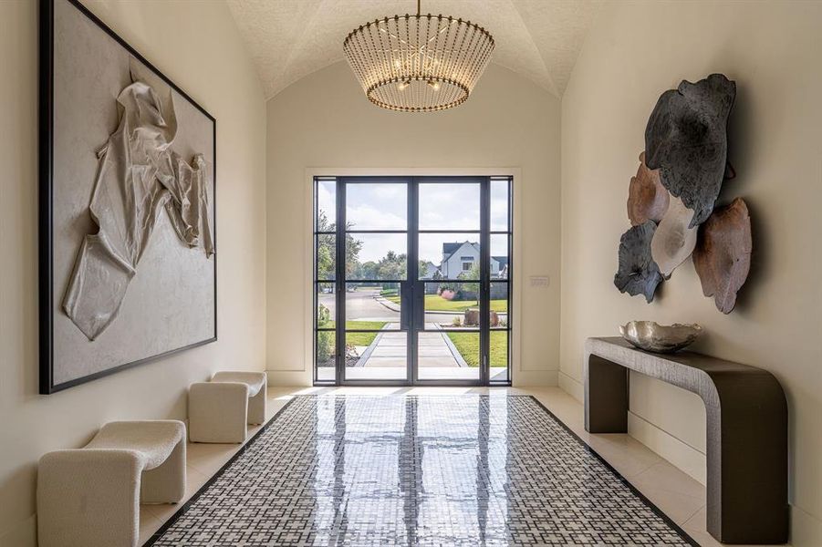 Doorway to outside featuring lofted ceiling, tile patterned flooring, and a chandelier