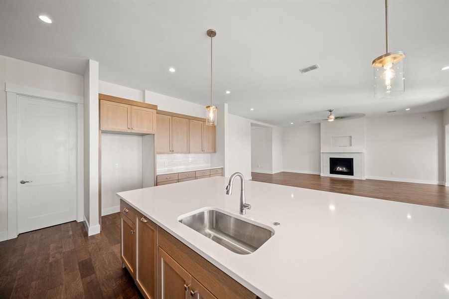 Kitchen with hanging light fixtures, dark wood-style flooring, recessed lighting, backsplash, and open floor plan