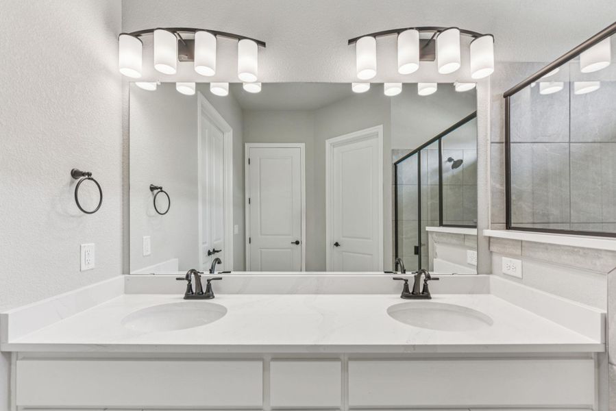 Full bathroom with a textured wall, a shower stall, and double vanity Full bathroom with a textured wall, a shower stall, and double vanity