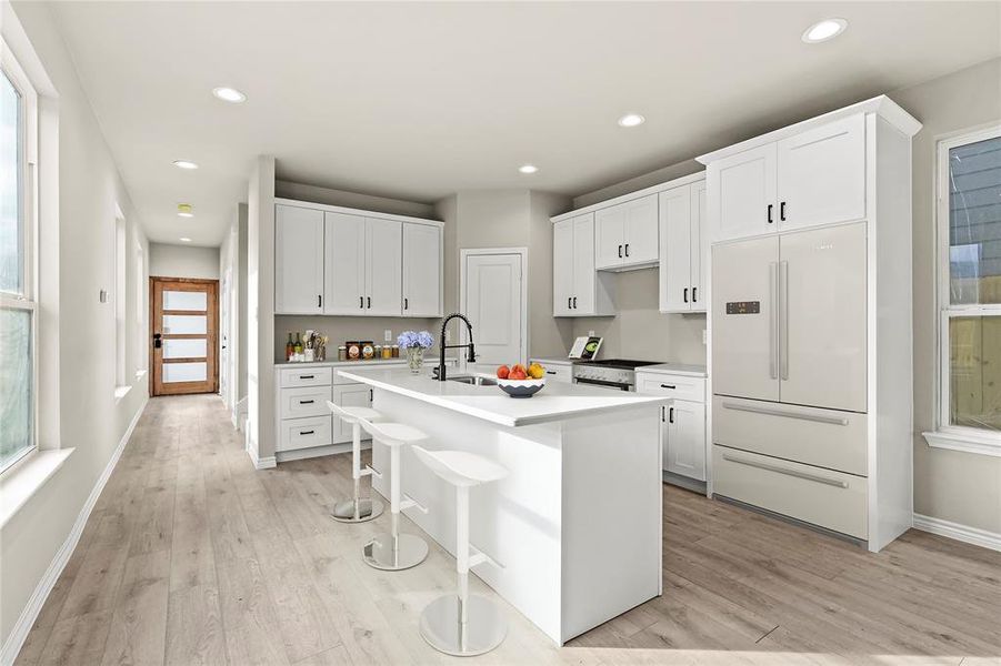 *Virtually Staged* Kitchen with built in fridge, a healthy amount of sunlight, a center island with sink, and light hardwood / wood-style floors