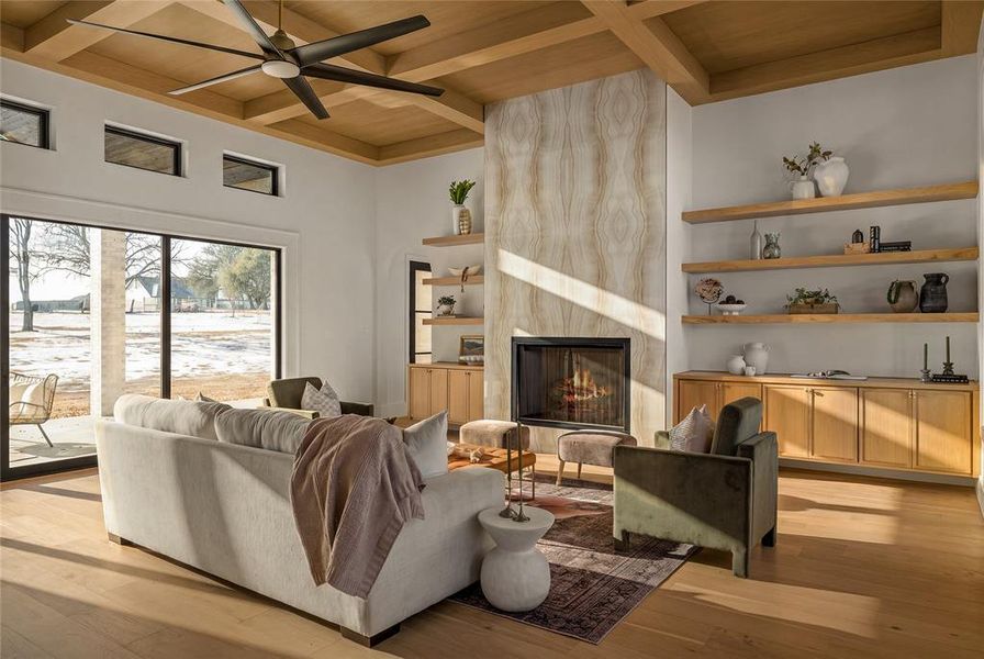 Spacious living area featuring a coffered wood-finish ceiling, a fireplace with a stone-look surround, wood-finish flooring, and expansive sliding glass doors