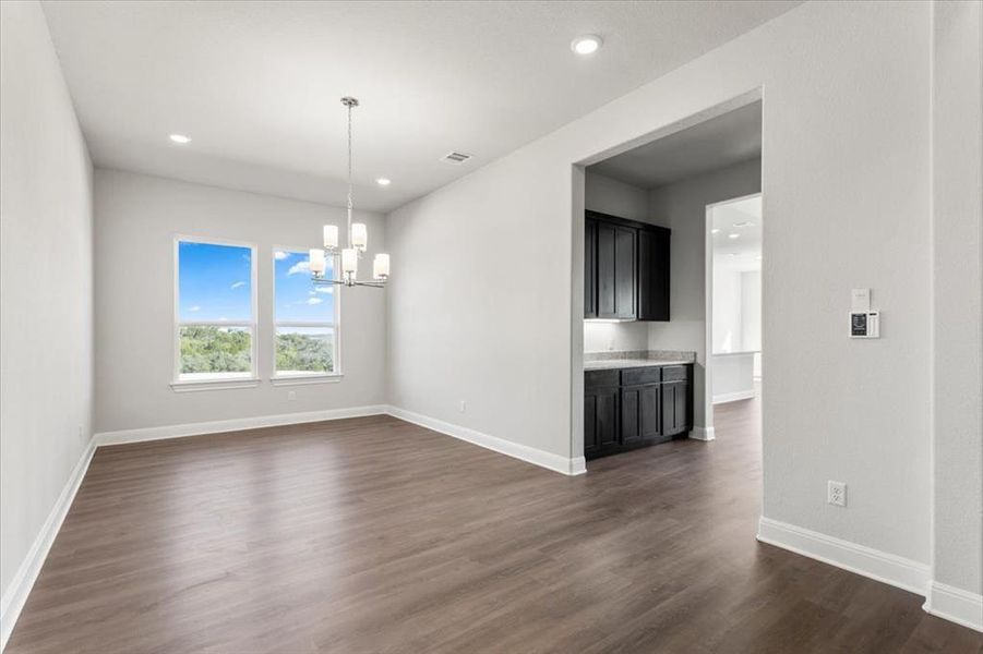Unfurnished dining area with hanging lights and dark wood-type flooring