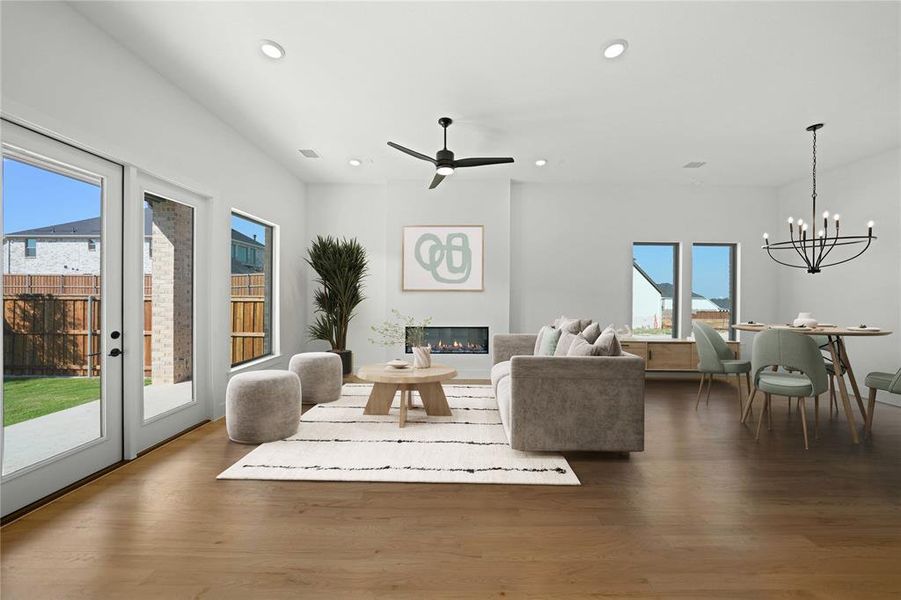 Living area featuring a glass covered fireplace, dark wood-type flooring, recessed lighting, ceiling fan, and a chandelier Living area featuring a glass covered fireplace, dark wood-type flooring, recessed lighting, ceiling fan, and a chandelier