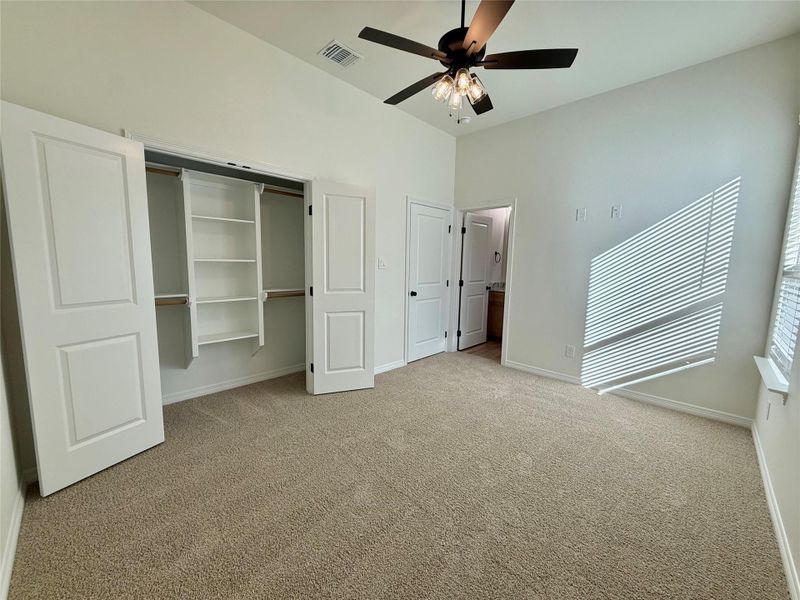 Unfurnished bedroom with a closet, light colored carpet, ceiling fan, and connected bathroom