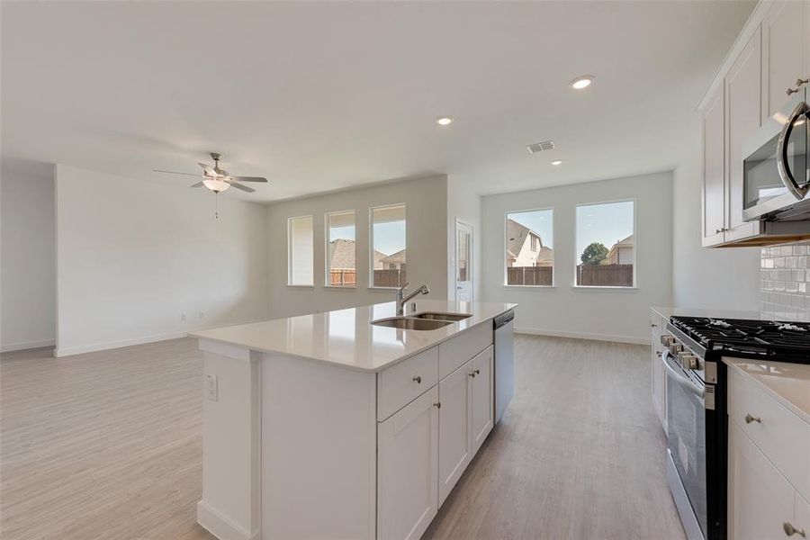 Kitchen featuring white cabinets, appliances with stainless steel finishes, a kitchen island with sink, and sink