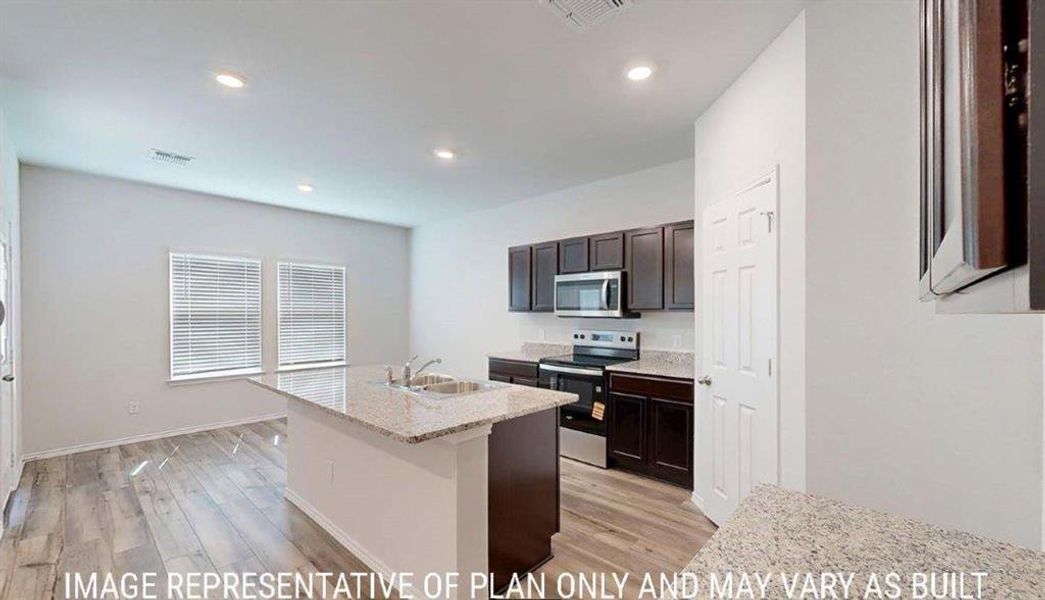 Modern kitchen featuring a central island with an undermount sink, granite countertops, and dark wood cabinetry Modern kitchen featuring a central island with an undermount sink, granite countertops, and dark wood cabinetry