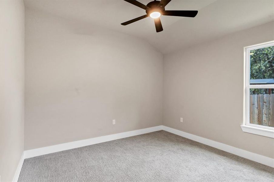 Spare room featuring carpet flooring, lofted ceiling, and ceiling fan Spare room featuring carpet flooring, lofted ceiling, and ceiling fan