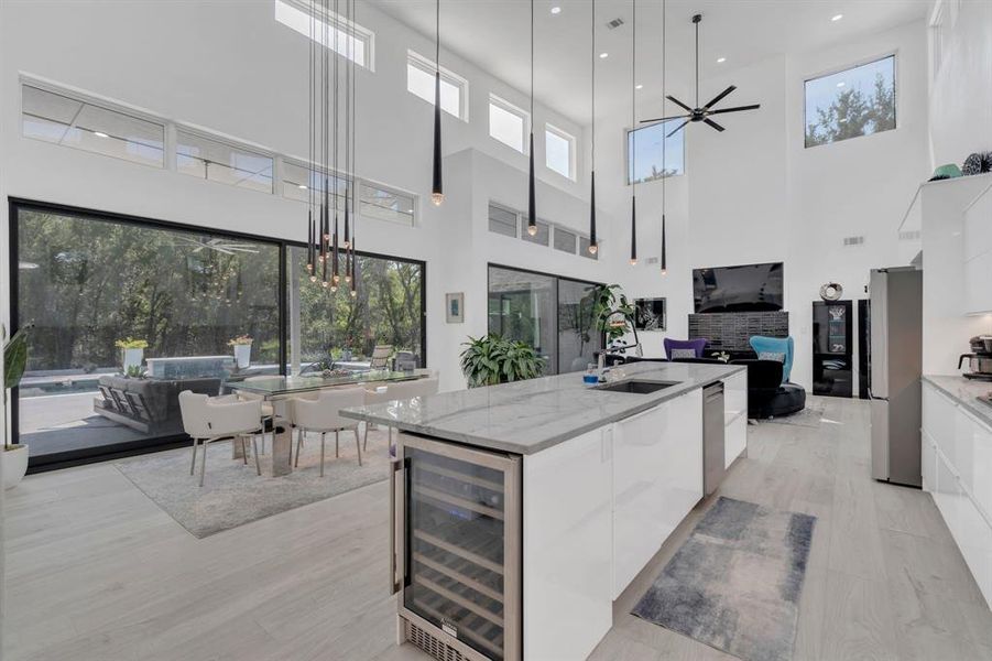 Kitchen with modern cabinets, white cabinetry, a high ceiling, and recessed lighting