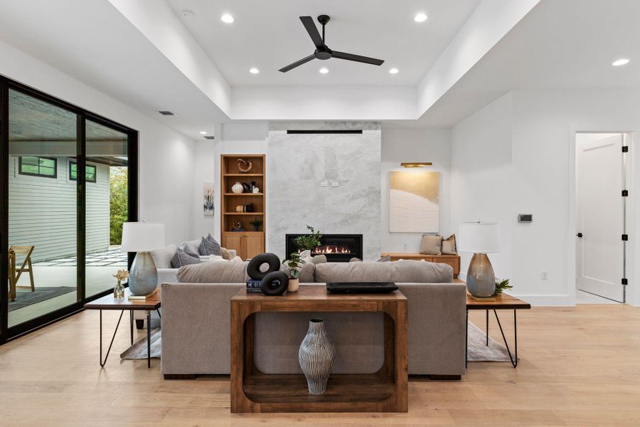 Living area with a ceiling fan, light wood-style floors, a tiled fireplace, recessed lighting, and baseboards