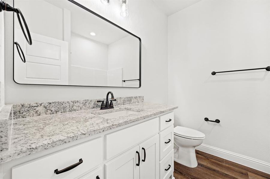 Bathroom featuring vanity, toilet, and wood-type flooring