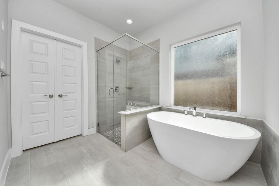 Escape to a spa-like oasis in this primary bathroom. Enjoy a walk-in shower with tile surround, a separate garden tub with custom detailing, and an elegant vanity featuring light countertops, modern hardware, and beautiful vanity lights. Experience luxury and relaxation in every detail.