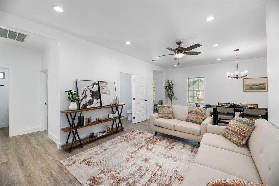 Living room with recessed lighting, light wood-style flooring, a ceiling fan, and a chandelier Living room with recessed lighting, light wood-style flooring, a ceiling fan, and a chandelier