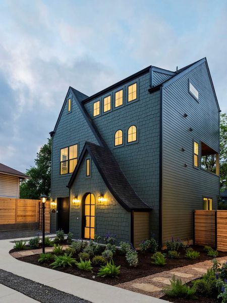 View of front facade with an attached garage, driveway, and a gate
