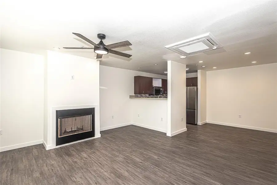 living room featuring ceiling fan,  wood-type flooring, and a textured ceiling