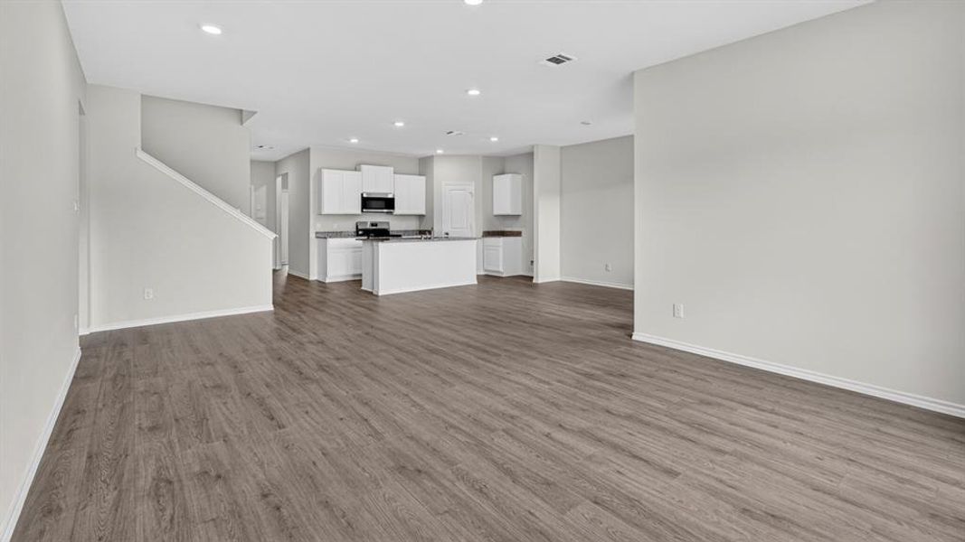 Open-concept living space featuring wood-finish flooring, recessed lighting, and a neutral wall palette Open-concept living space featuring wood-finish flooring, recessed lighting, and a neutral wall palette