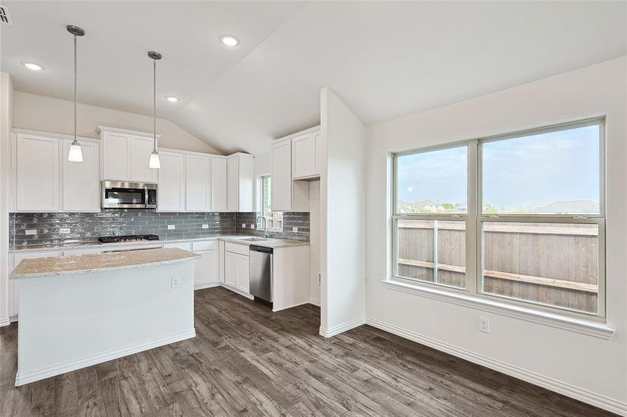 Kitchen with lofted ceiling, stainless steel appliances, white cabinetry, and dark hardwood / wood-style flooring