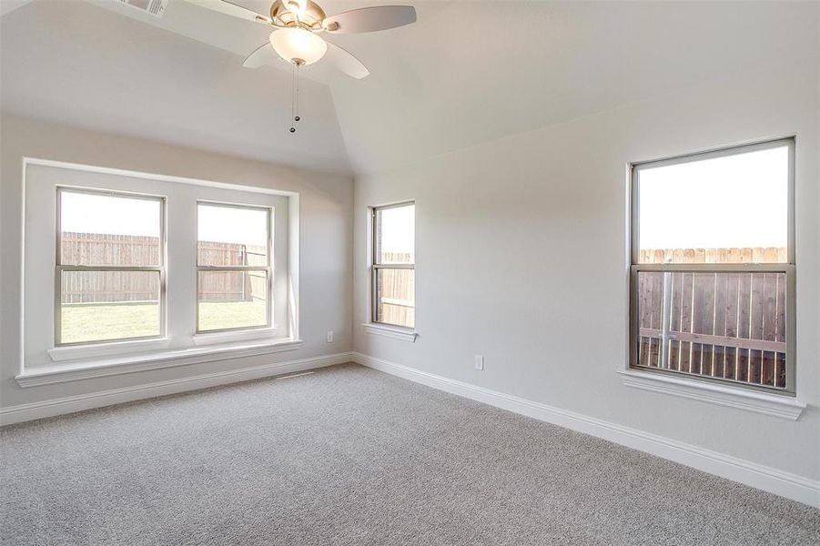 Carpeted empty room with lofted ceiling and ceiling fan